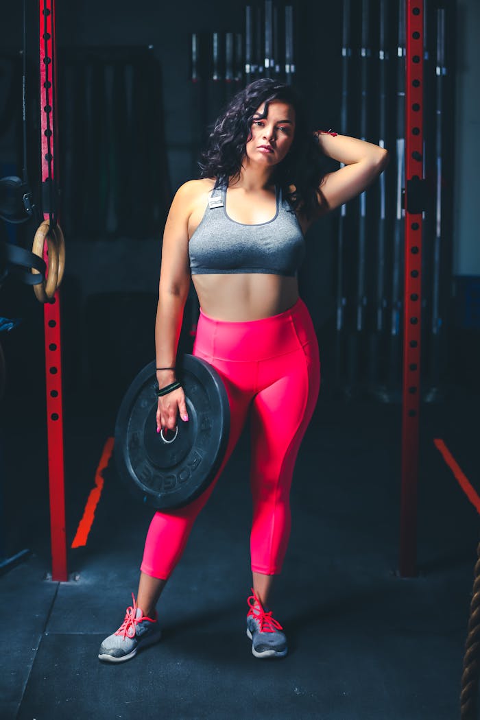 Confident woman in gym attire holding a weight, showcasing fitness and strength.